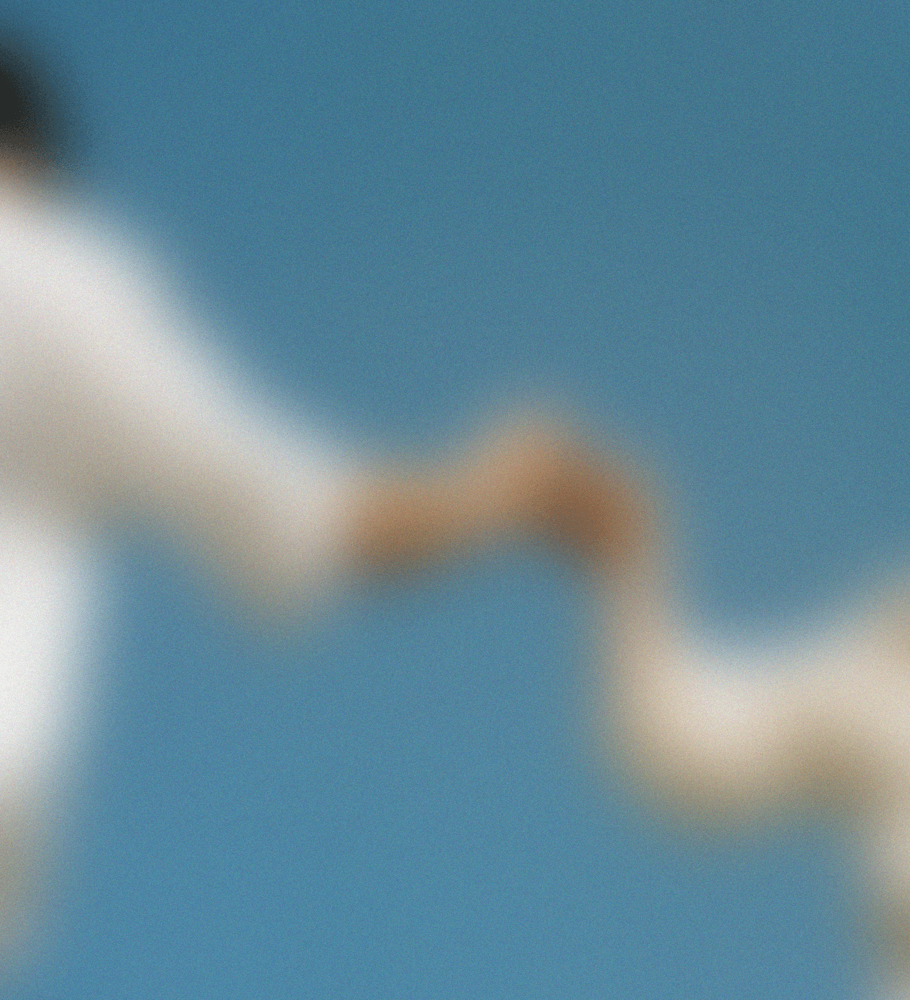 Two hands reaching toward each other against a blue sky